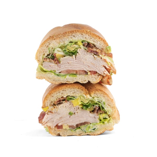 Two halves of a Hollywood Wraps & Grill turkey sandwich with lettuce, tomato, and bacon.