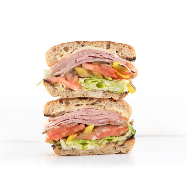 Hollywood Wraps & Grill's ham and cheese sandwich with lettuce, tomato, and pickles, cut in half.