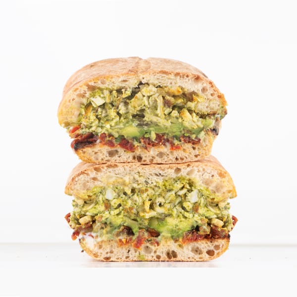 A Hollywood Wraps & Grill sandwich, cut in half, revealing avocado, sun-dried tomatoes, and egg salad.